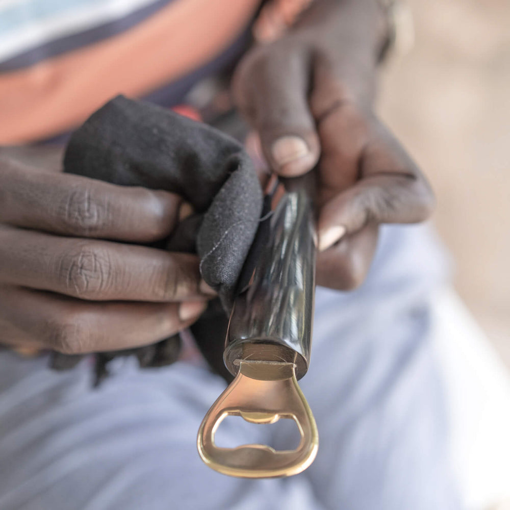 
                  
                    Ugandan artisan hand-polishing Ankole horn and brass bottle opener Fairkind ethically sourced and handmade in Uganda.
                  
                