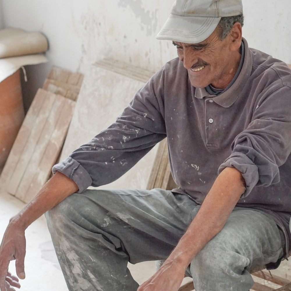 Moroccan artisan laughing while at work at ceramics workshop in Safi, Morocco. The Safi Ceramists, partners with Fairkind.