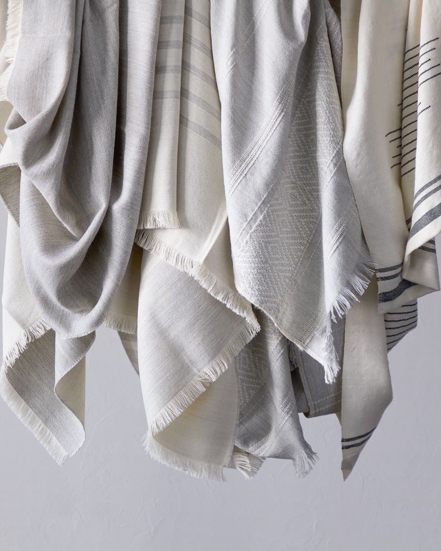 Group of gray and white alpaca throw blankets hanging. 100% handmade baby alpaca from Peru.
