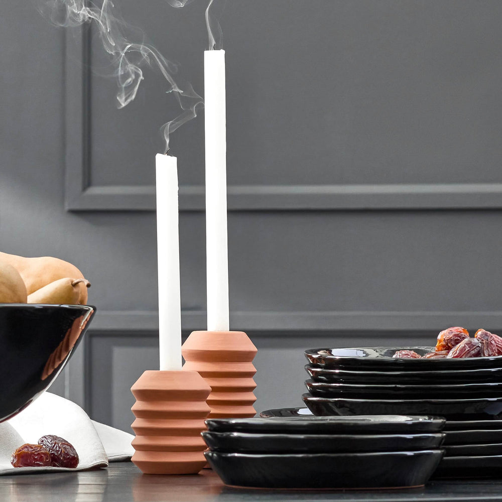 Fall holiday tableware against dark gray wall. Modern dinnerware and handmade clay candle holders.