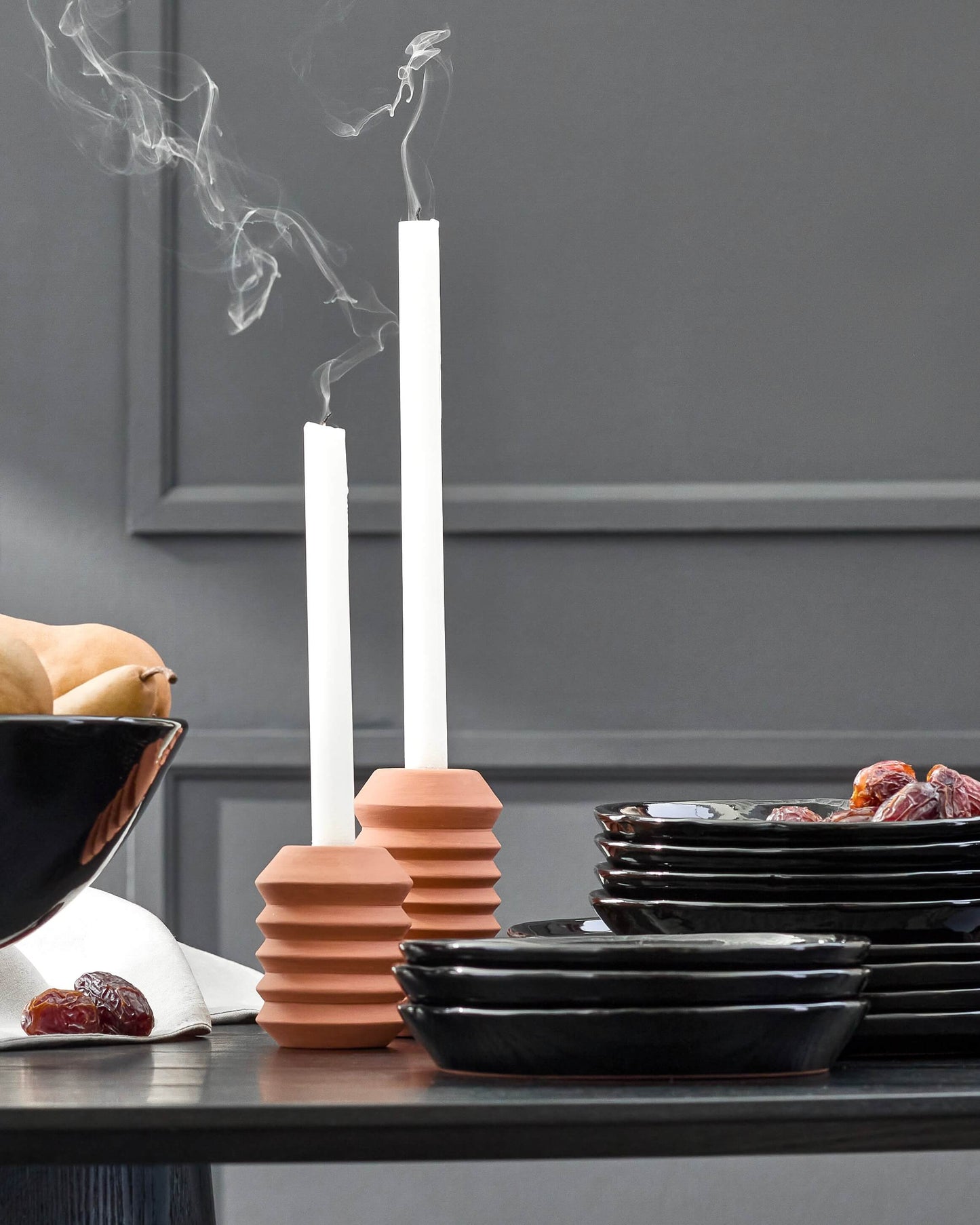 Fall holiday tableware against dark gray wall. Modern dinnerware and handmade clay candle holders.