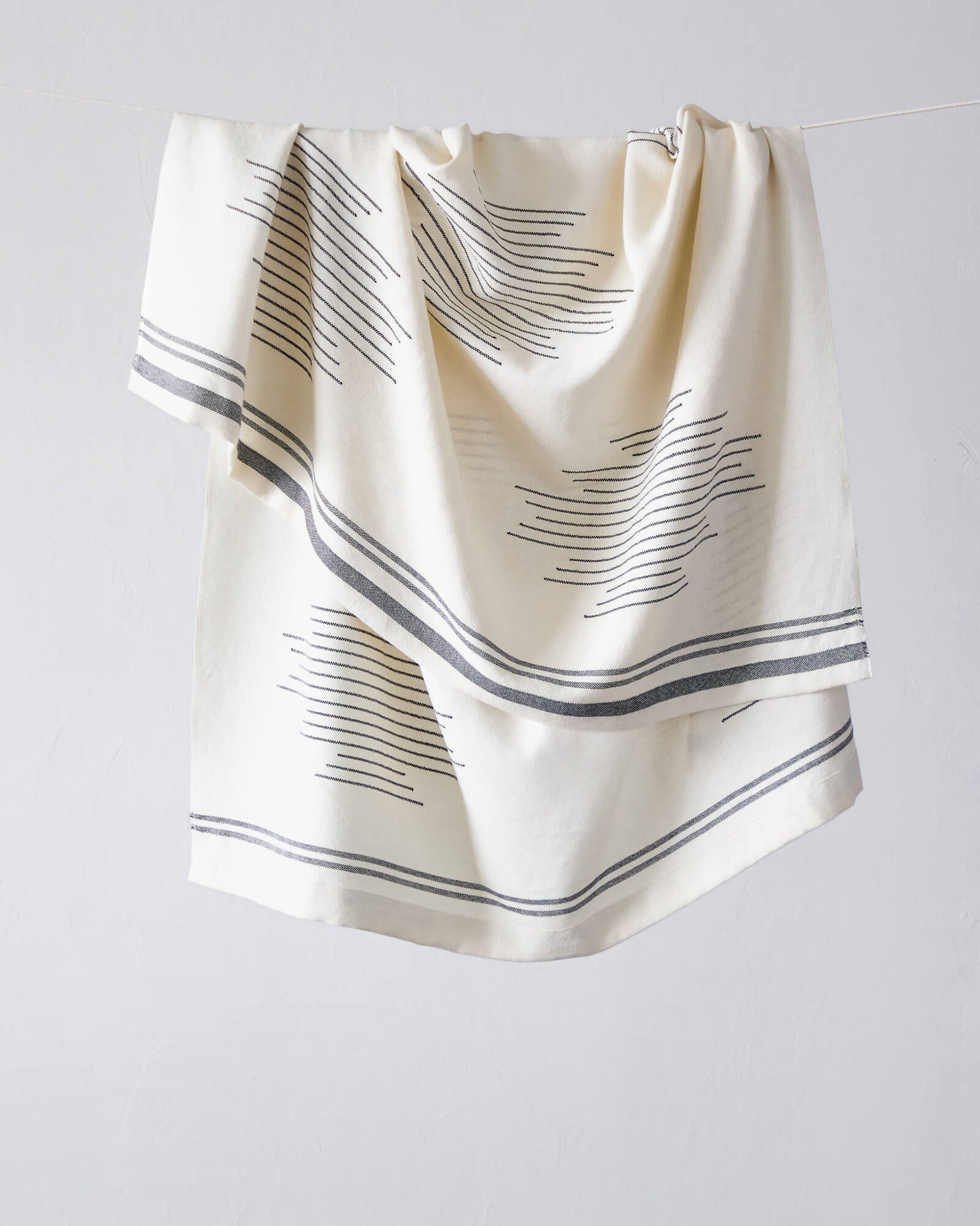 Fairkind Isleño luxury white and black alpaca throw blanket with folded edge and modern design.