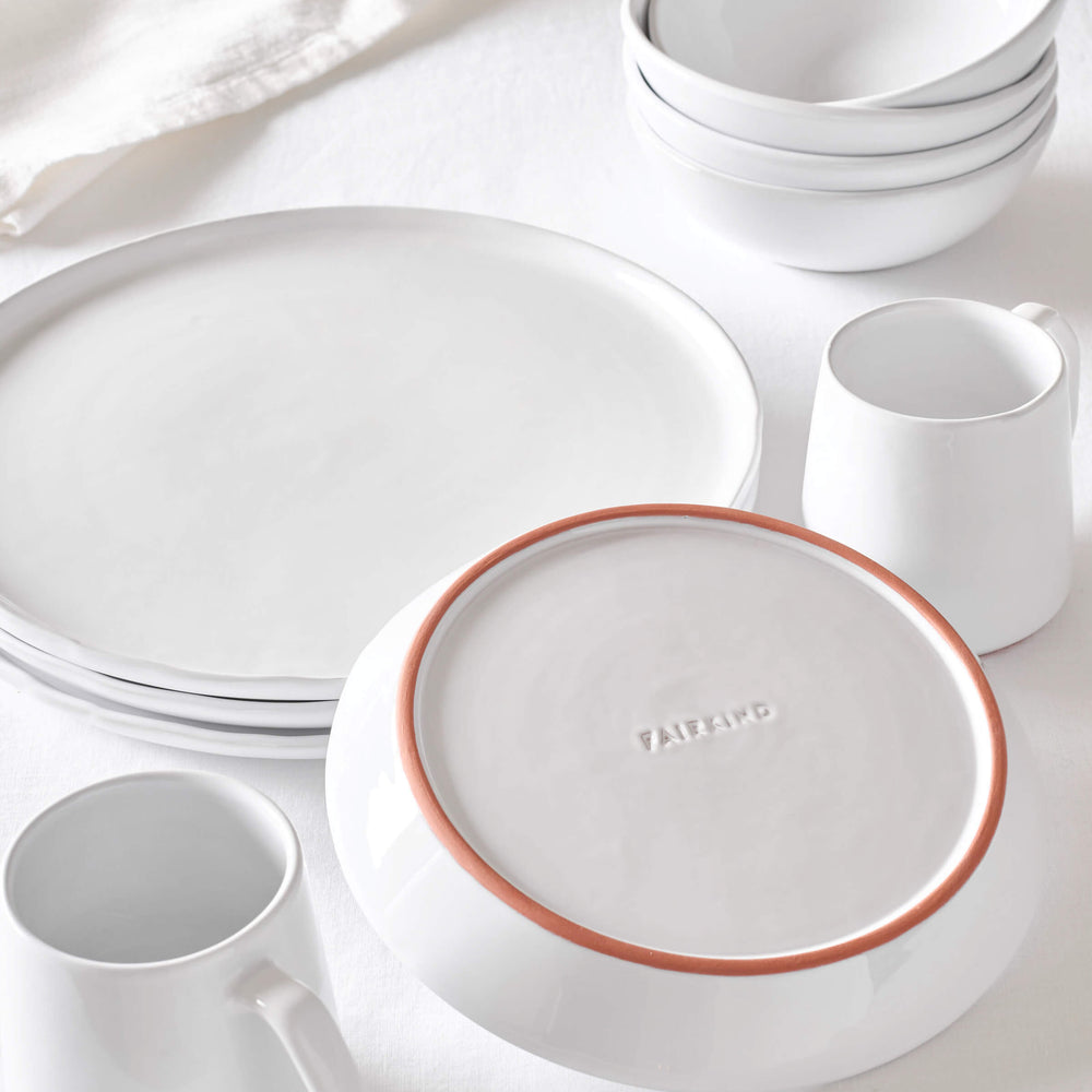 Modern, white ceramic dinnerware handcrafted in Morocco styled as a collection against a white background.