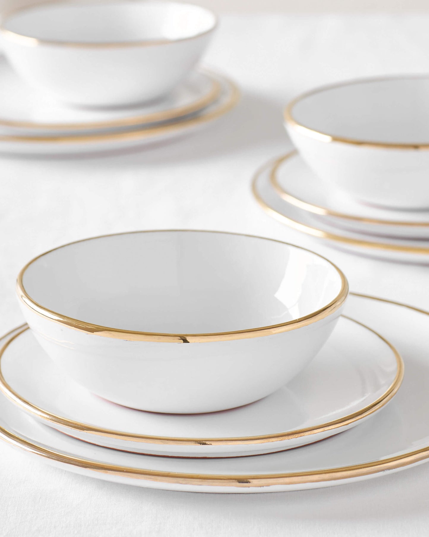 
                  
                    Three sets of Fez Gold-Rimmed dinnerware by Fairkind. Handmade by master ceramists in Morocco.
                  
                