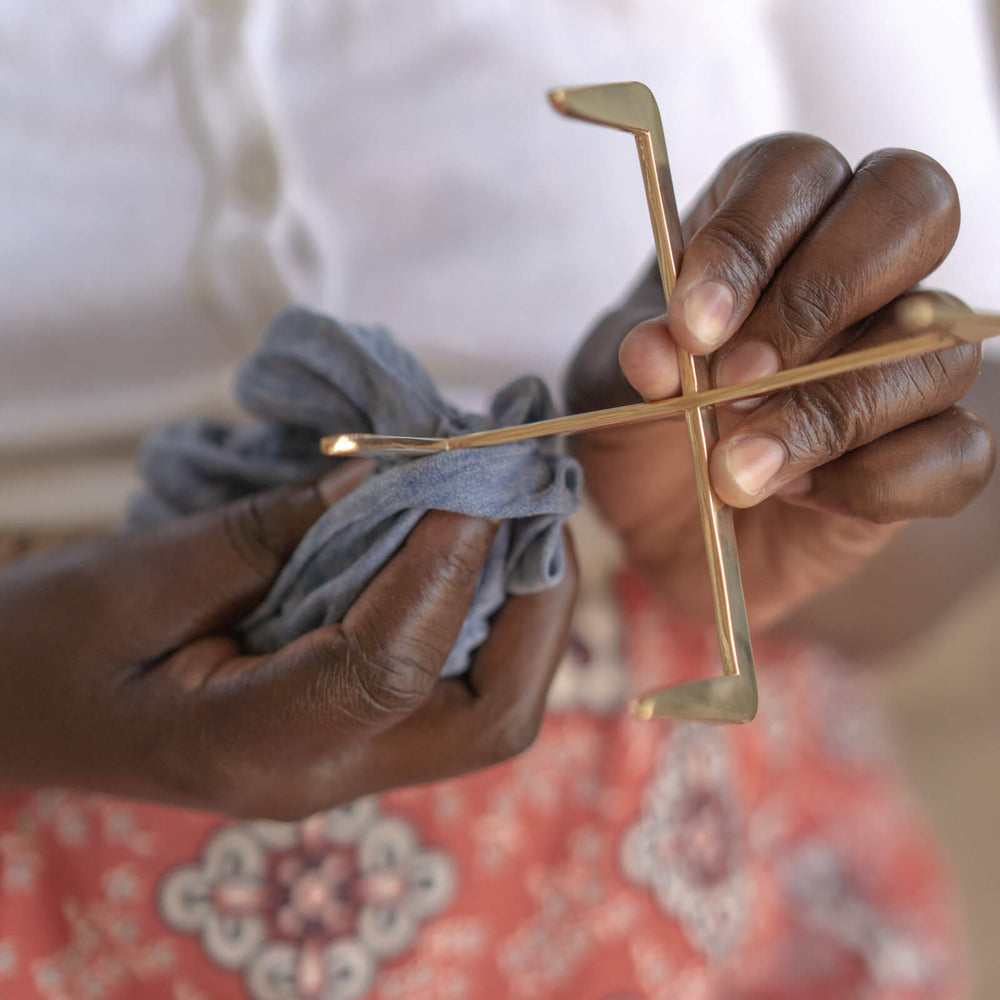 
                  
                    Ugandan artisan polishing brass coaster holder by hand.
                  
                
