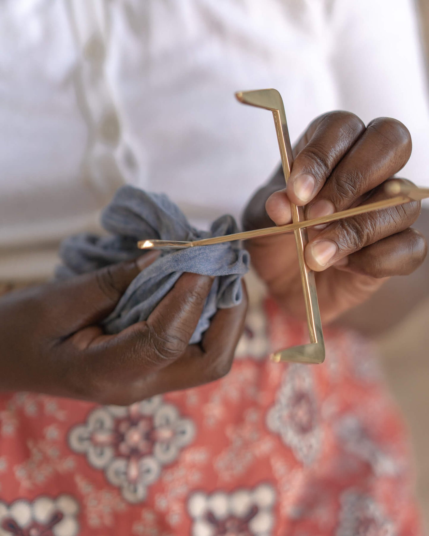 
                  
                    Ugandan artisan polishing brass coaster holder by hand.
                  
                