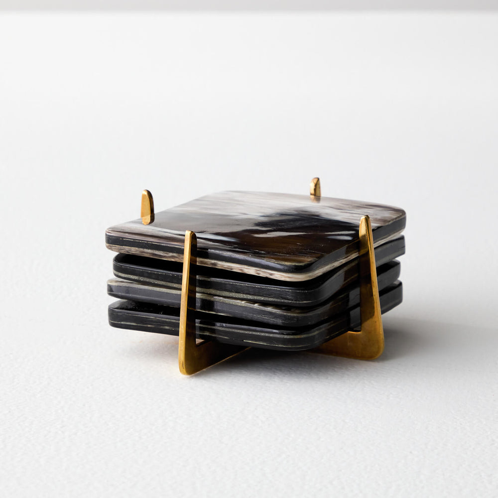 
                  
                    Set of four coasters in brass holder made by artisans with ethically sourced horn.
                  
                