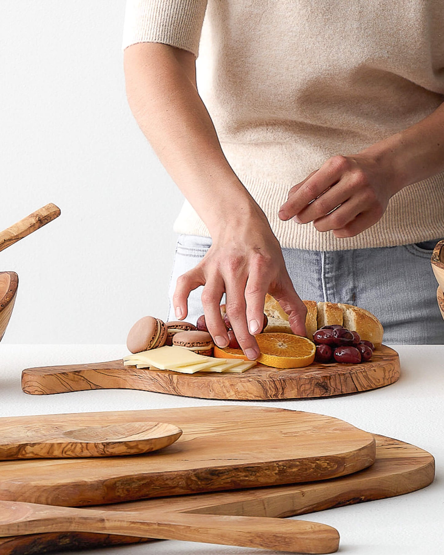 
                  
                    Woman preparing cheese board on Fairkind's Chebika Bread Board.
                  
                