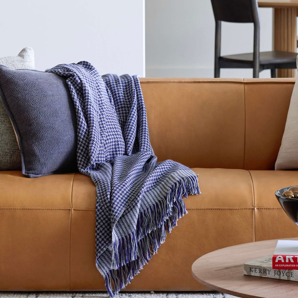 Living room with modern leather couch and blue checkered alpaca throw. Luxury interior design.