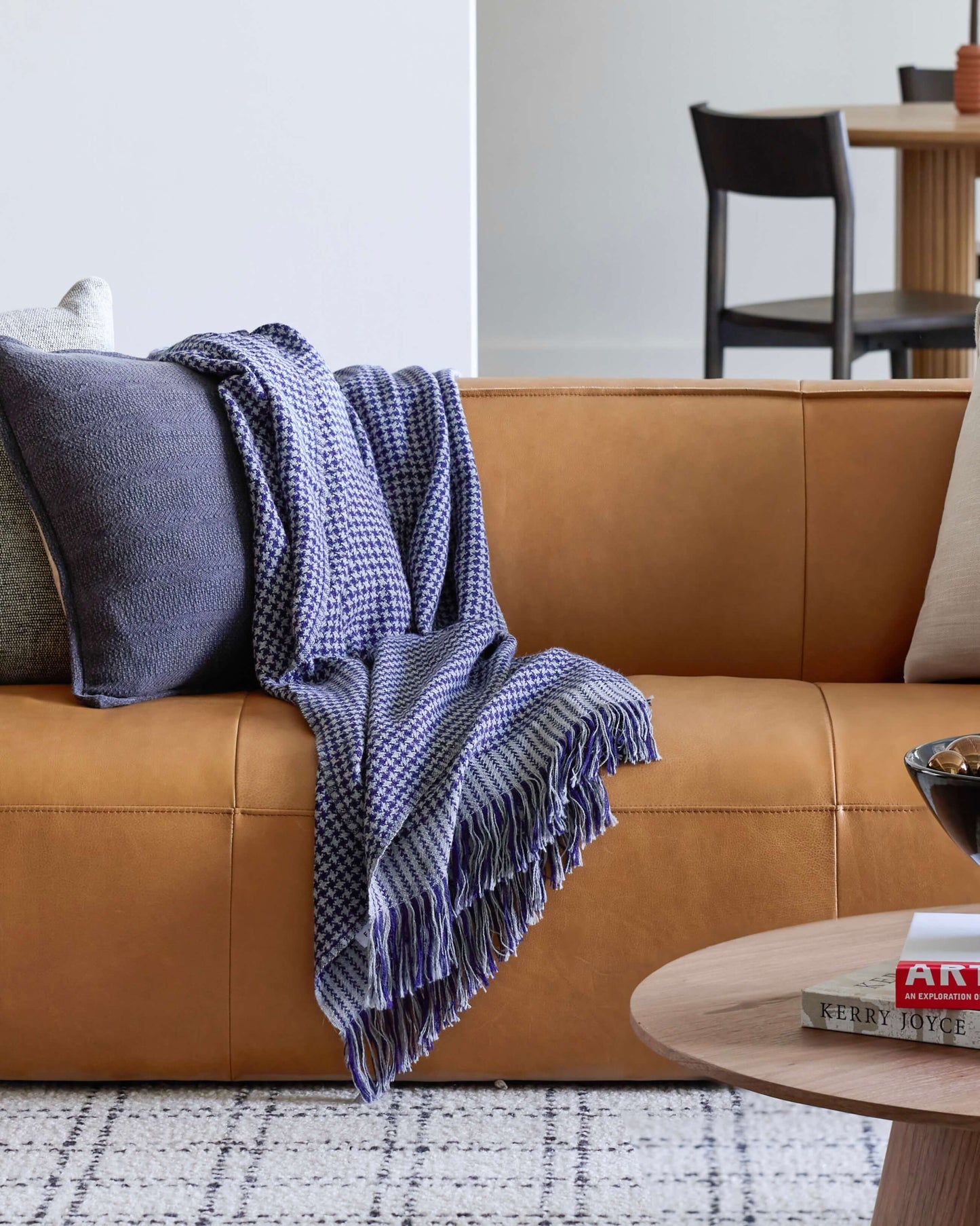 Living room with modern leather couch and blue checkered alpaca throw. Luxury interior design.
