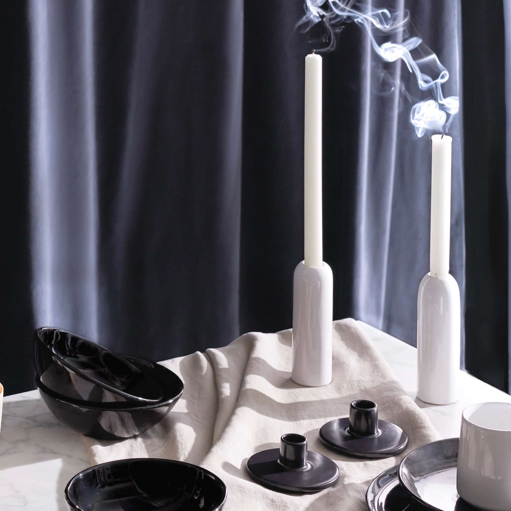 
                  
                    Luxury holiday table decor including glossy white ceramic taper holders with white candles and billowing smoke.
                  
                