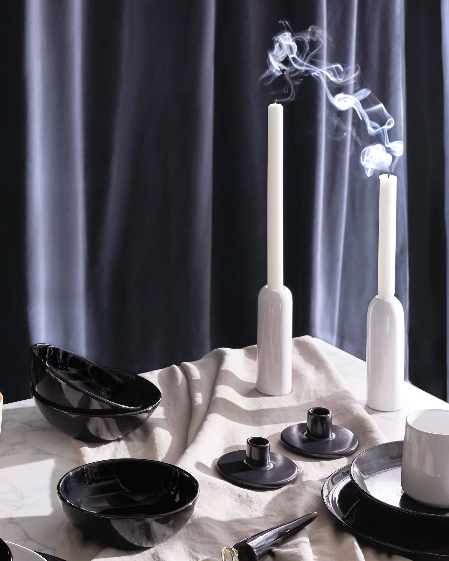 
                  
                    Luxury holiday table decor including glossy white ceramic taper holders with white candles and billowing smoke.
                  
                