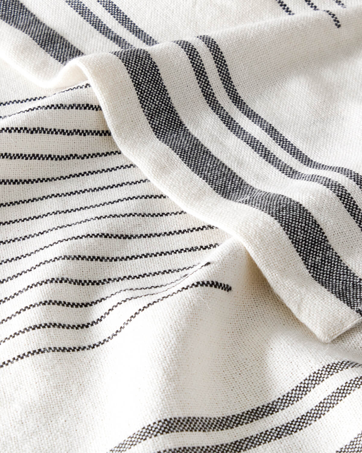 Detail of Fairkind Isleño baby alpaca throw folded edge white with charcoal details.