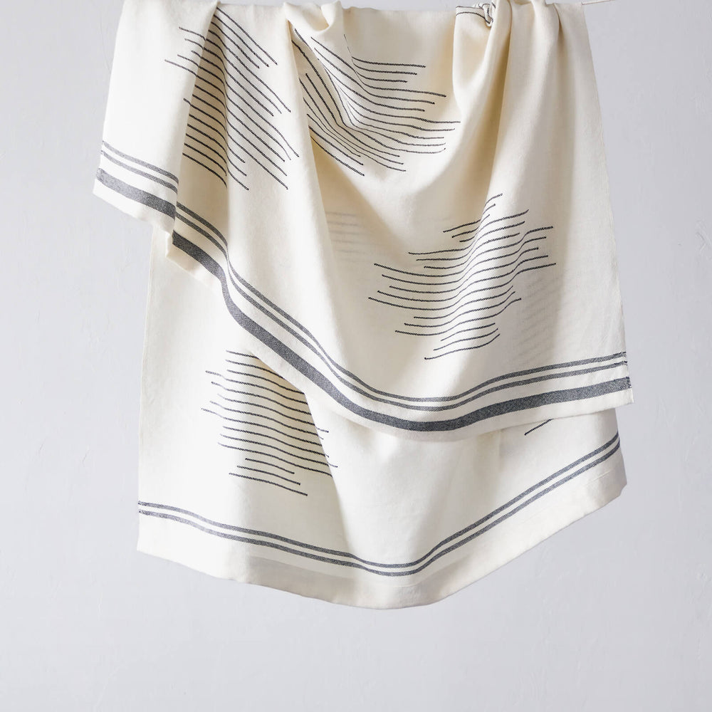 
                  
                    Fairkind Isleño luxury white and black alpaca throw blanket with folded edge and modern design.
                  
                