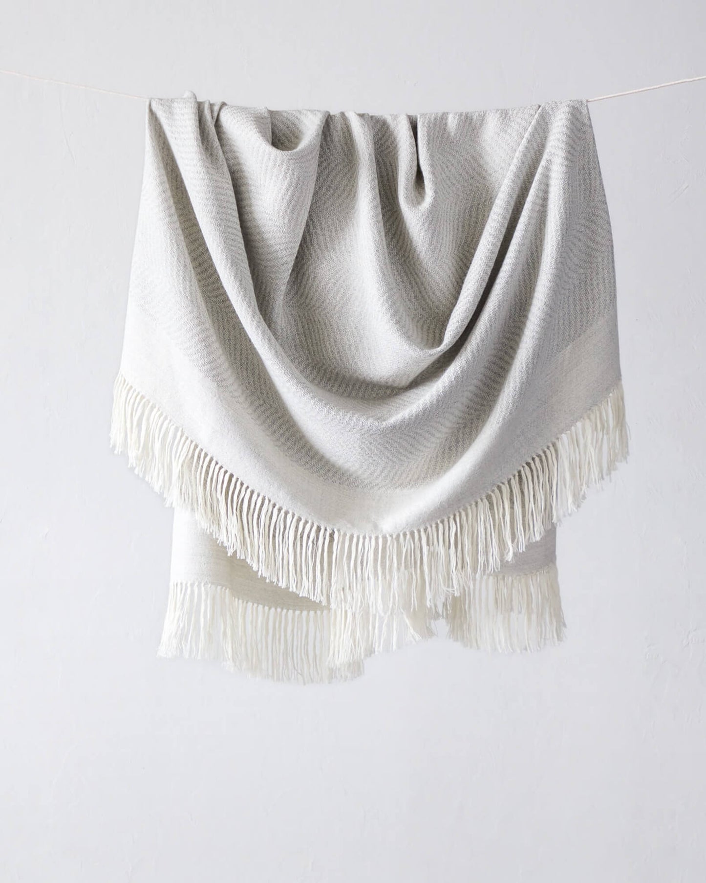 
                  
                    La Loma Fairkind light gray baby alpaca throw with long white fringe made in Peru.
                  
                