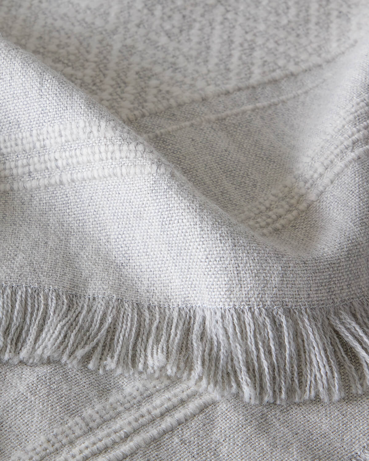 
                  
                    Detail of La Marea super soft baby alpaca blanket by Fairkind handwoven in Peru with textured stripes and fringe.
                  
                