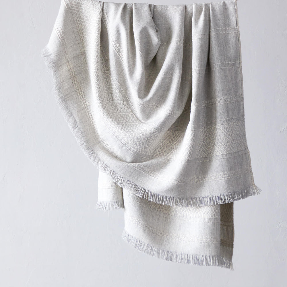 La Marea Alpaca Throw by Fairkind. Light gray textured baby alpaca throw blanket with fringe.