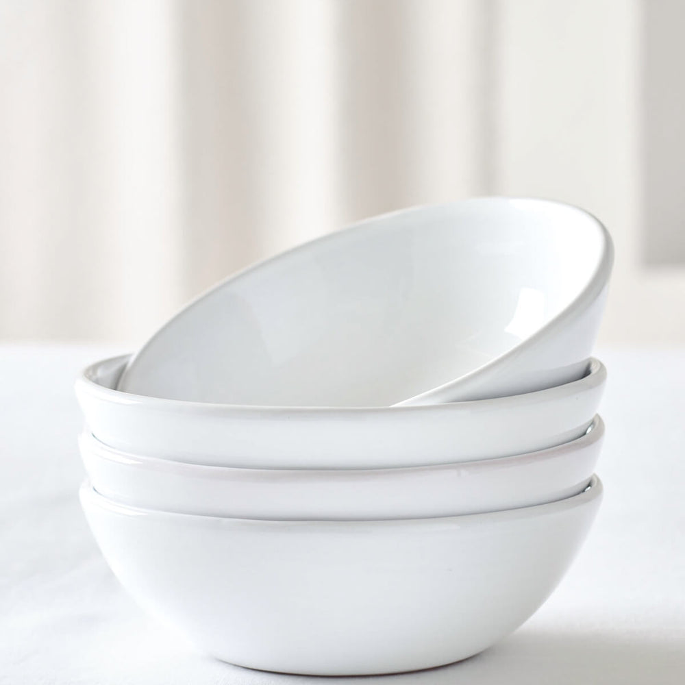 
                  
                    Khira Soup Bowls by Fairkind stacked on white table. Modern, white ceramic dinnerware.
                  
                