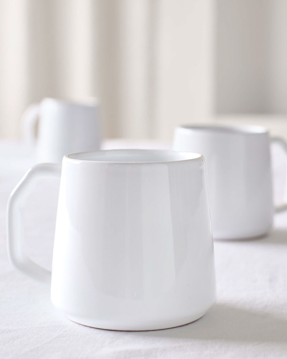 Modern, minimal white ceramic mugs with angled handles, handmade in Morocco.