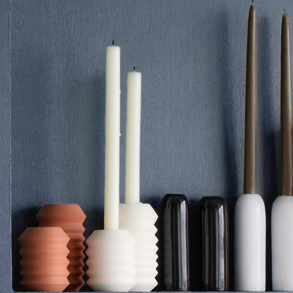 
                  
                    Taper candle holders from Fairkind's Morocco Collection lined up against blue wall.
                  
                