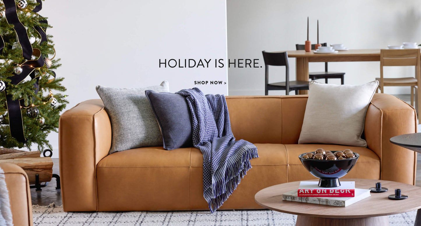 Modern holiday living room with leather couch, christmas tree and handmade decor and blankets by Fairkind.
