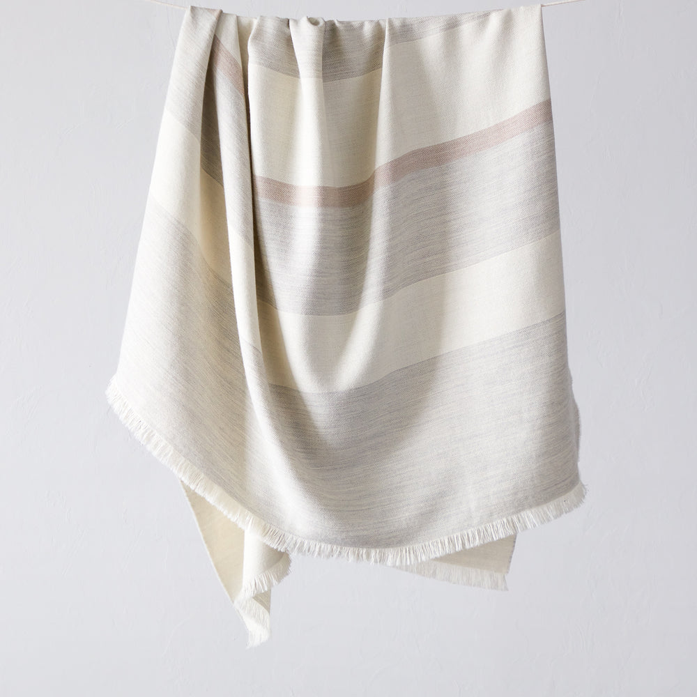 Altura Alpaca Throw by Fairkind. Light gray, white and blush stripes. Handwoven by artisans in Peru