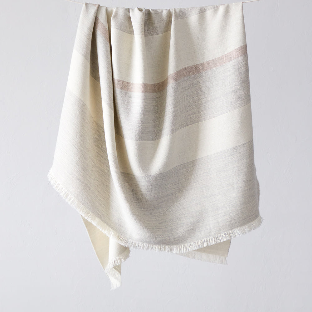 
                  
                    Altura Alpaca Throw by Fairkind. Light gray, white and blush stripes. Handwoven by artisans in Peru
                  
                