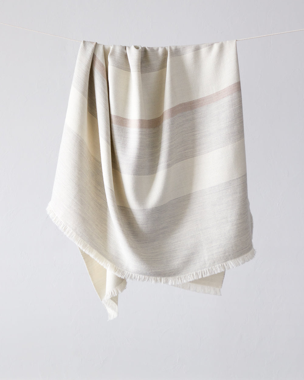 Altura Alpaca Throw by Fairkind. Light gray, white and blush stripes. Handwoven by artisans in Peru