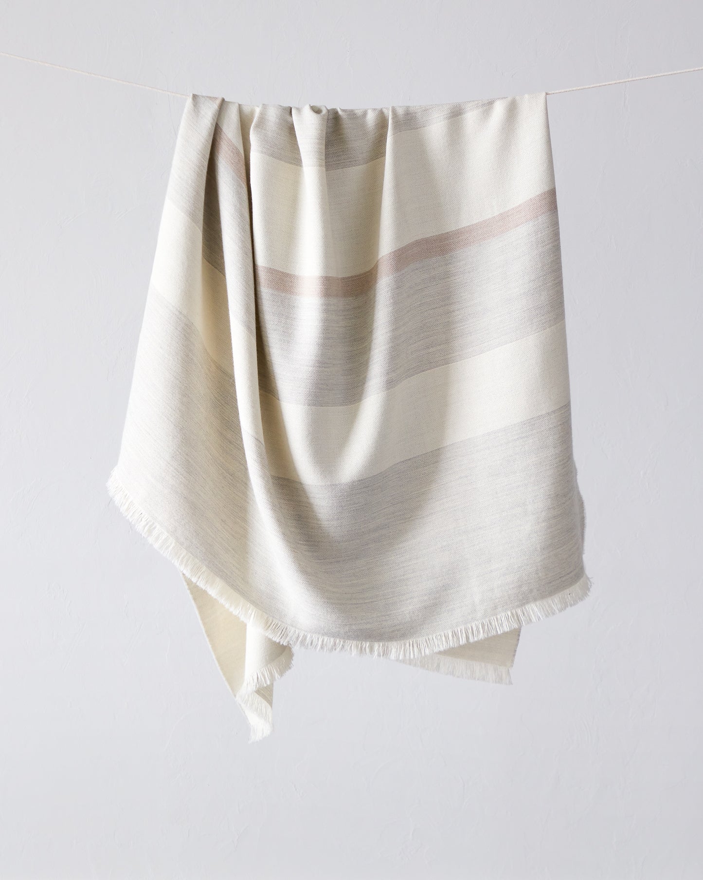 
                  
                    Altura Alpaca Throw by Fairkind. Light gray, white and blush stripes. Handwoven by artisans in Peru
                  
                