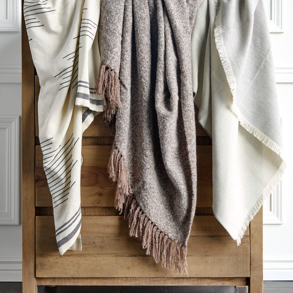 
                  
                    Isleño, La Tierra, and Soñando Alpaca Throw Blankets by Fairkind hanging on dresser.
                  
                