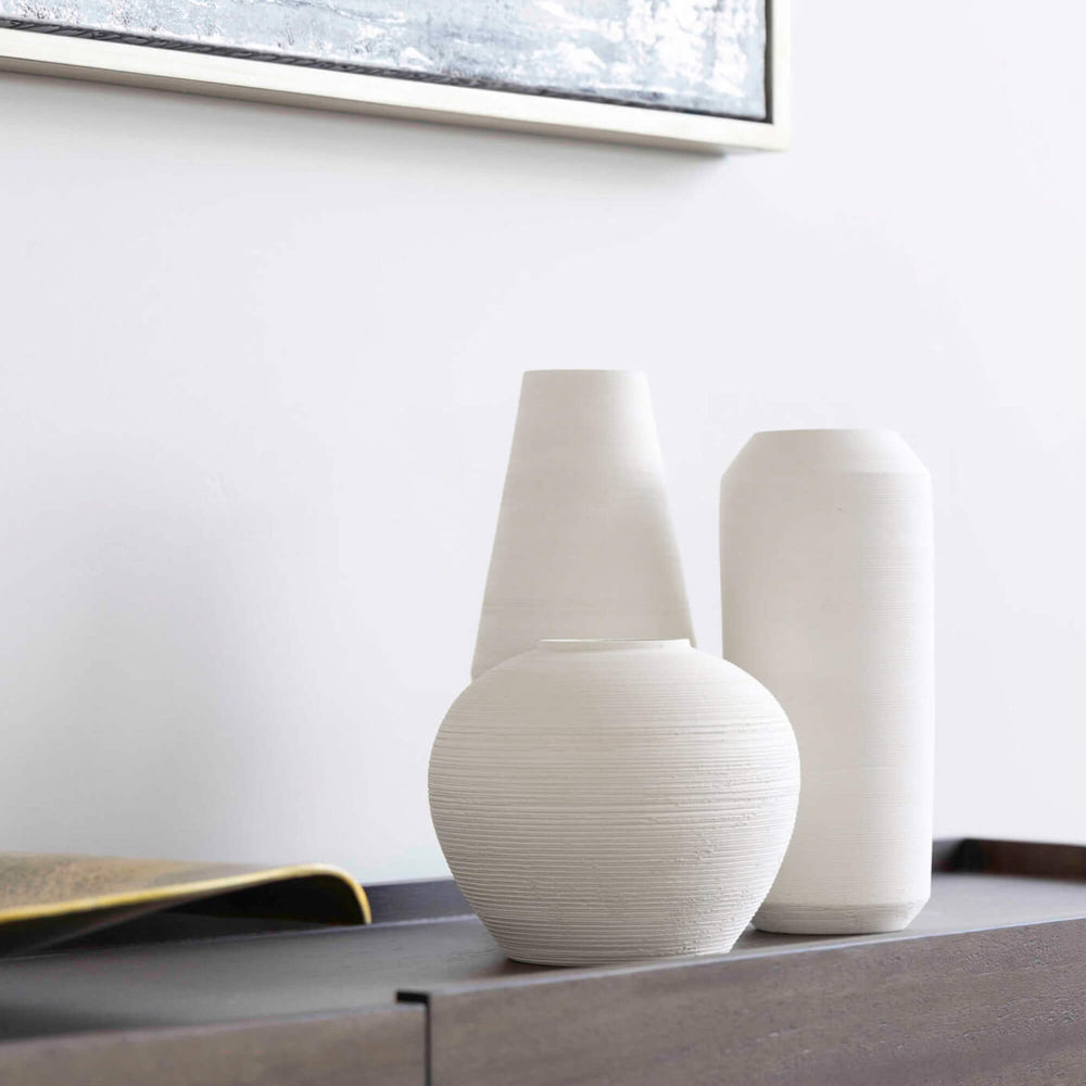 
                  
                    Fairkind's Zarina Vases on a black side table against a white textured wall. Handmade by master ceramists in Morocco.
                  
                