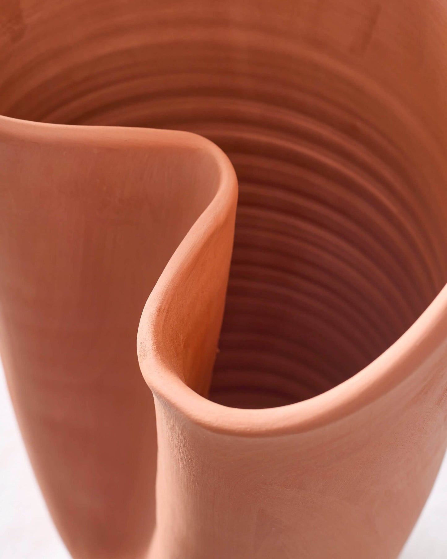 
                  
                    Close-up of curved vase edge of sculptural terracotta vase collection.
                  
                