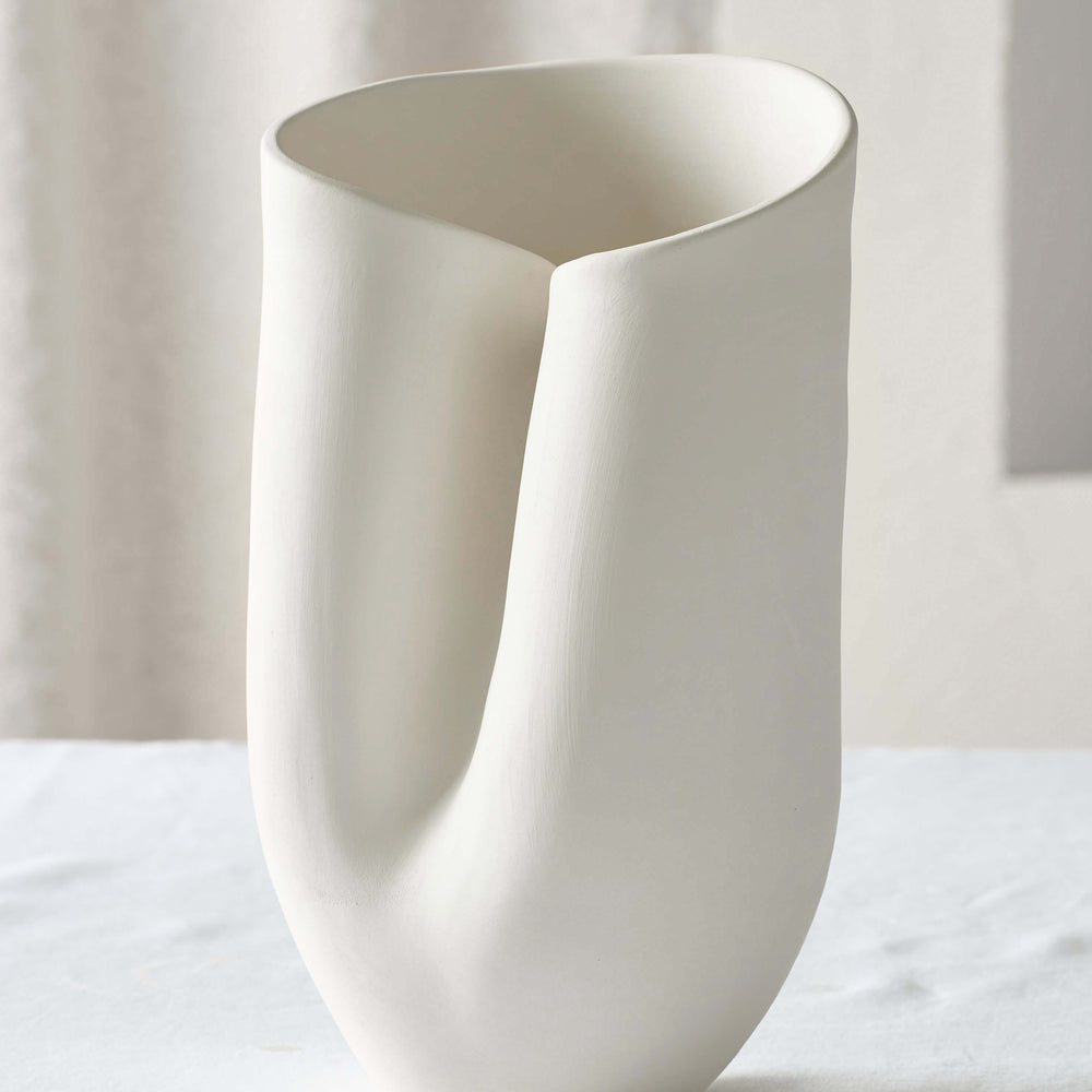 
                  
                    Large white Zoya Terracotta Vase on a white table. Abstract handcrafted vase with curved edge sculptural details and a textured finish.
                  
                