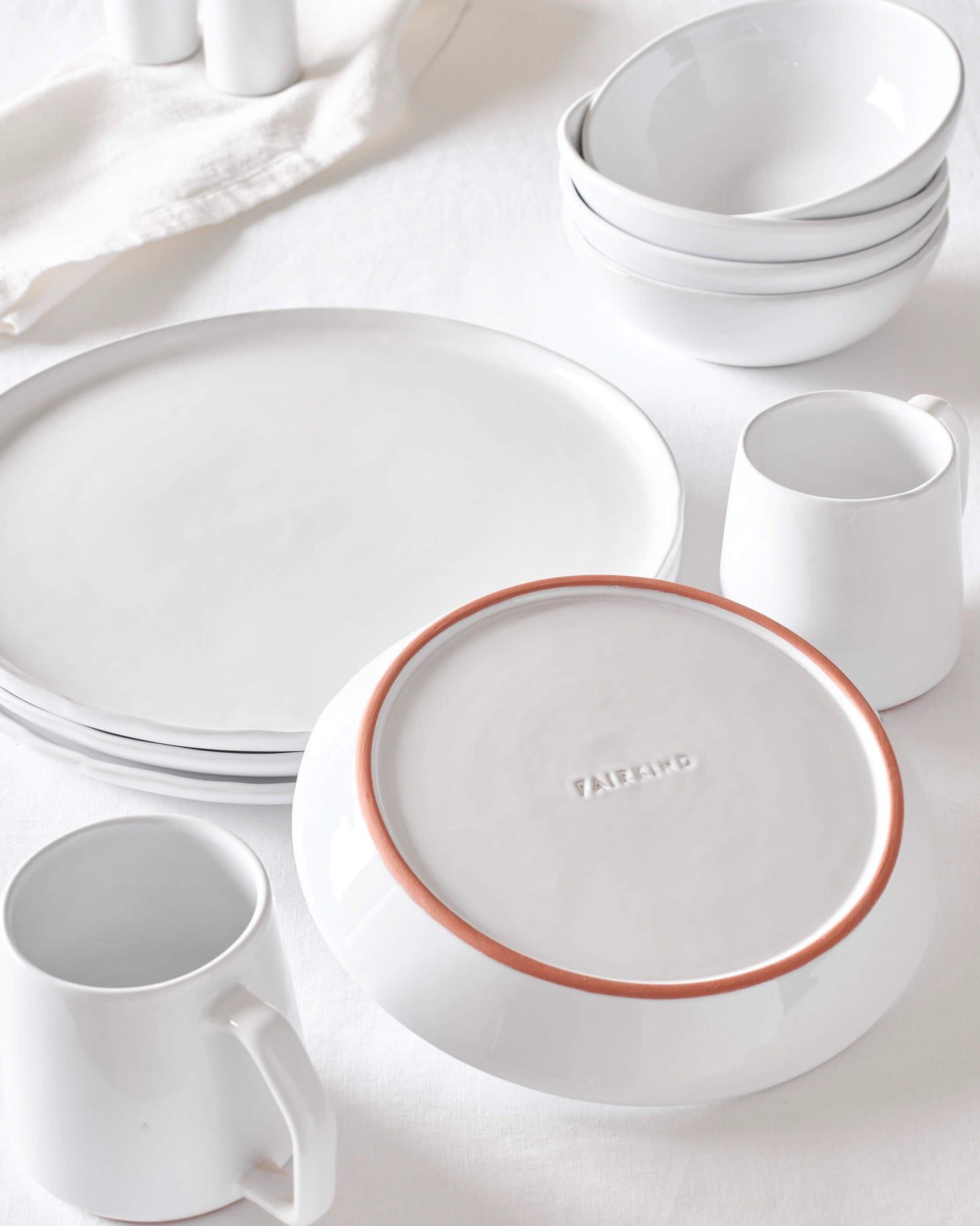 Modern, white ceramic dinnerware handcrafted in Morocco styled as a collection against a white background.