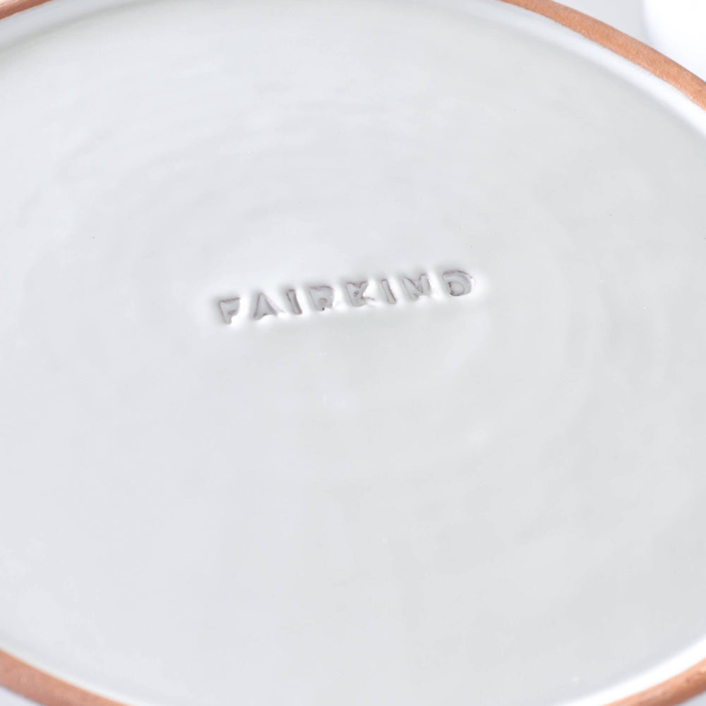
                  
                    Close-up of logo engraving on bottom of Khira Salad plate with red ceramic edge.
                  
                