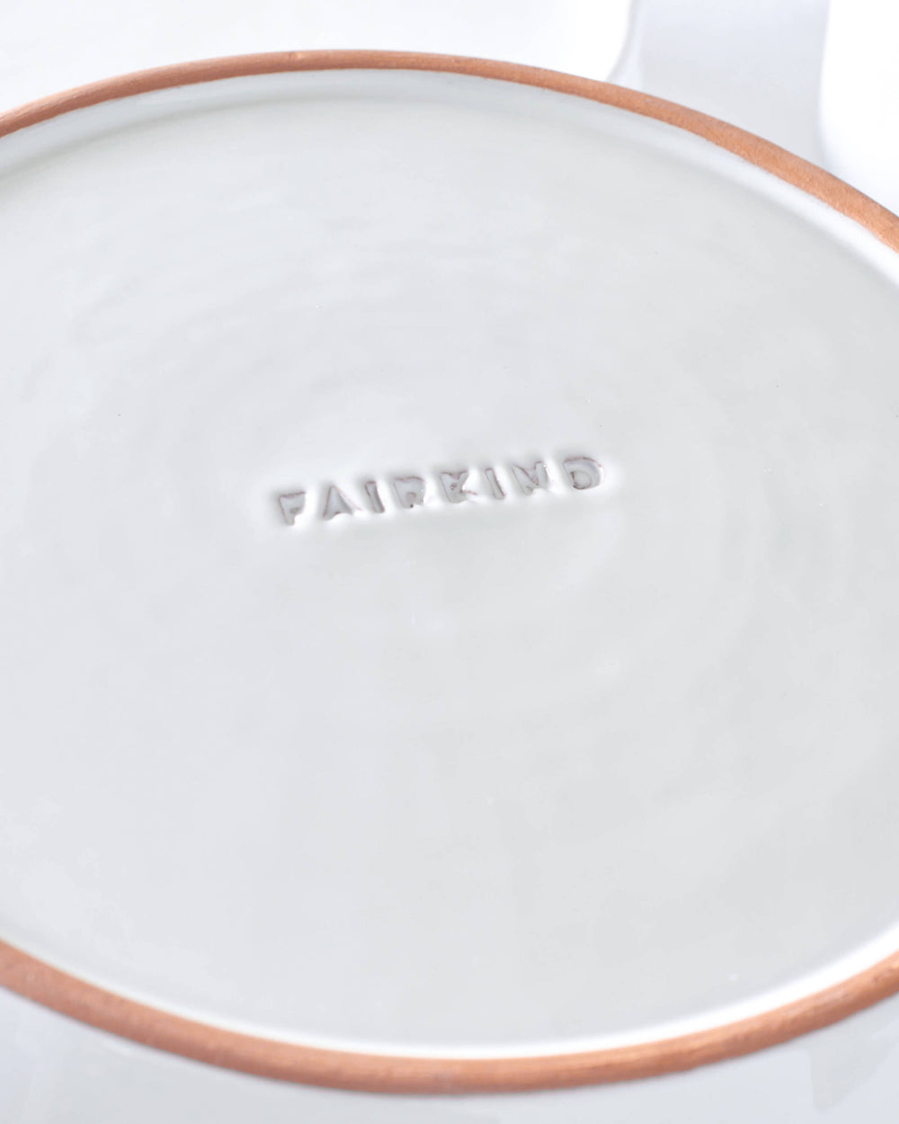 Close-up of logo engraving on bottom of Khira Salad plate with red ceramic edge.