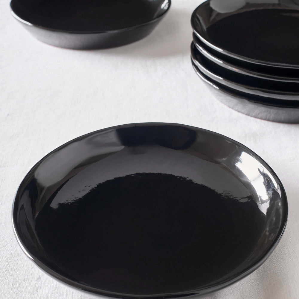 
                  
                    Black Riad Salad Plates by Fairkind stacked on white table. Part of the Morocco Ceramic Collection.
                  
                