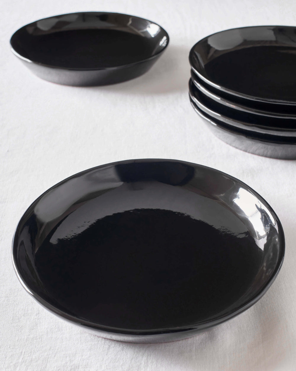 Black Riad Salad Plates by Fairkind stacked on white table. Part of the Morocco Ceramic Collection.