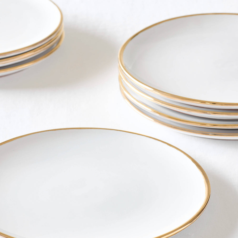 
                  
                    Fairkind's Fez Gold-Rimmed ceramic dinner plate stacked on white table.
                  
                