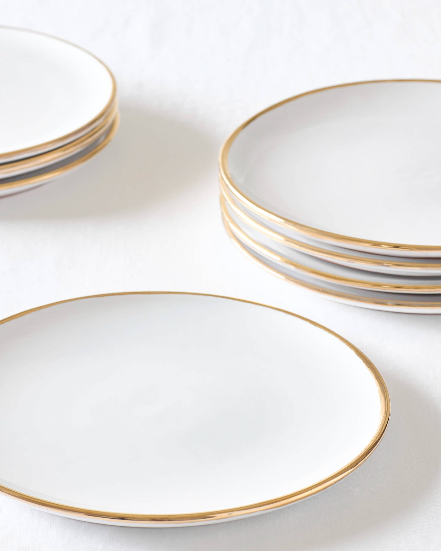 
                  
                    Fairkind's Fez Gold-Rimmed ceramic dinner plate stacked on white table.
                  
                