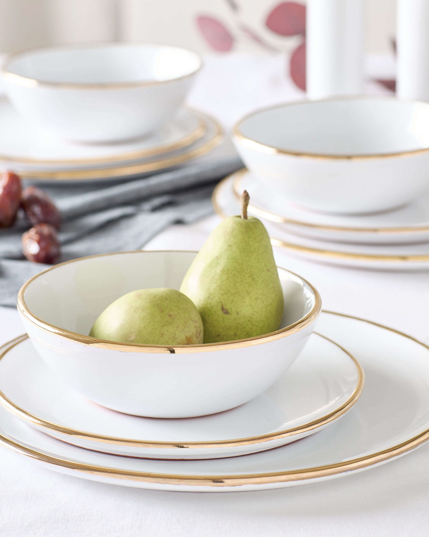 Fairkind's Fez Gold-Rimmed Dinnerware styled on a white table with pears.