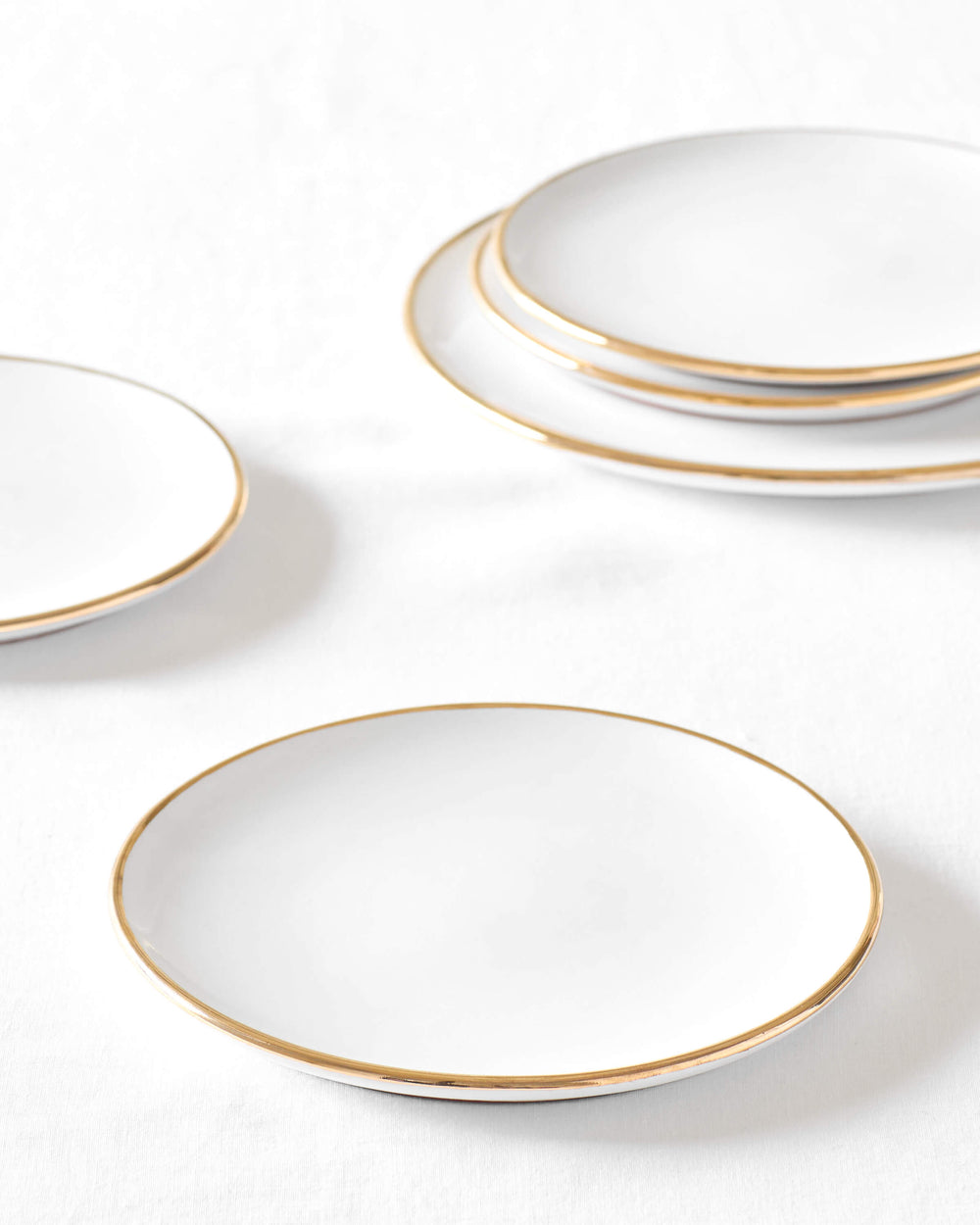 White ceramic salad plate with 18k gold edge on white background. Fez Dinnerware by Fairkind.