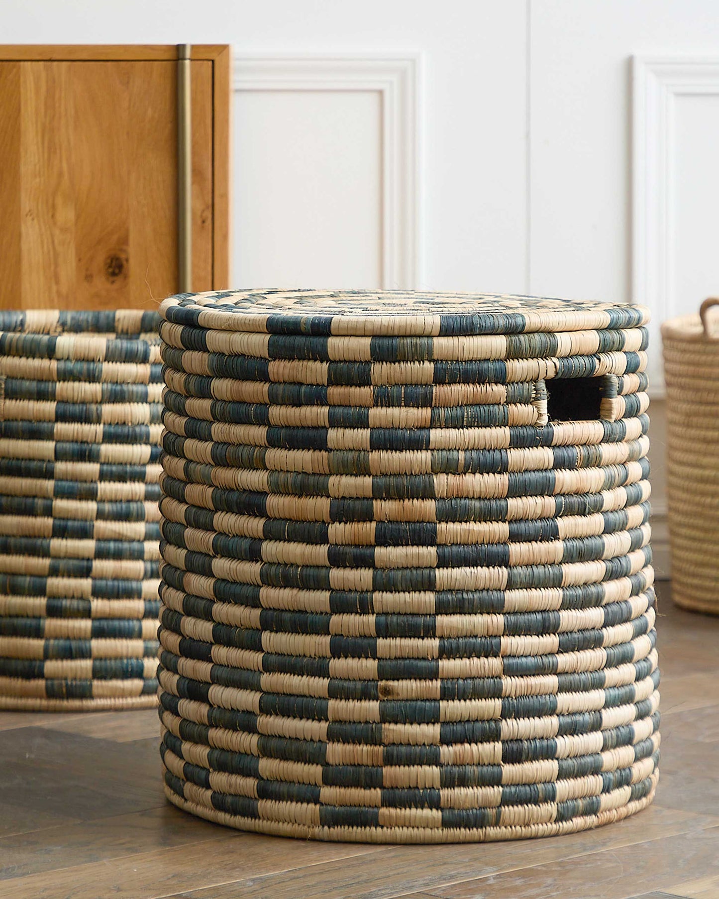 
                  
                    Set of checkered lidded storage baskets in modern living room. Malawi Collection by Fairkind.
                  
                
