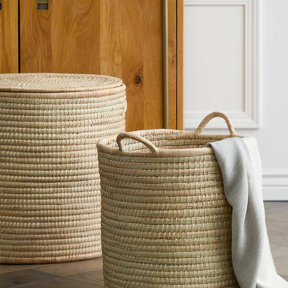
                  
                    Woven storage basket with handles holding throw blanket in modern living room. 
                  
                