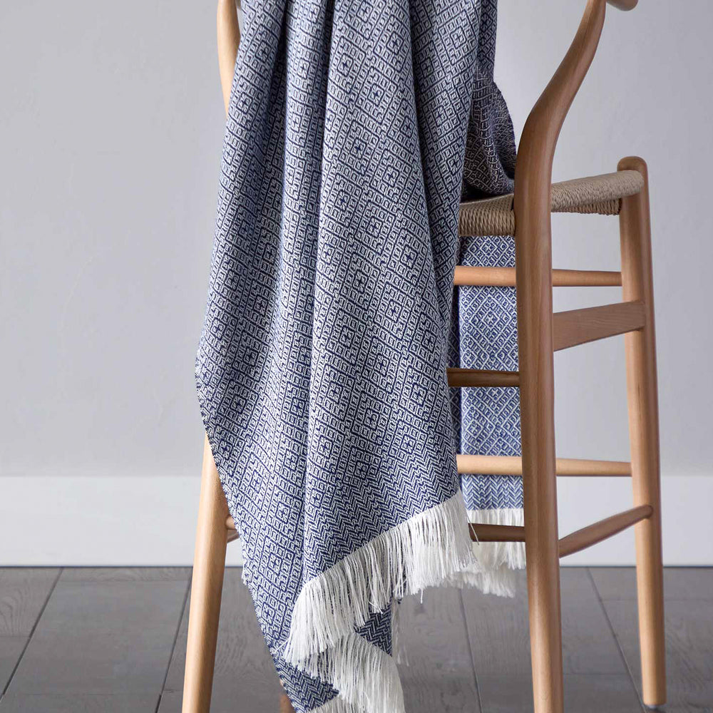 
                  
                    Styled navy blue baby alpaca throw blanket with white fringe modern design handcrafted by artisans in Peru.
                  
                