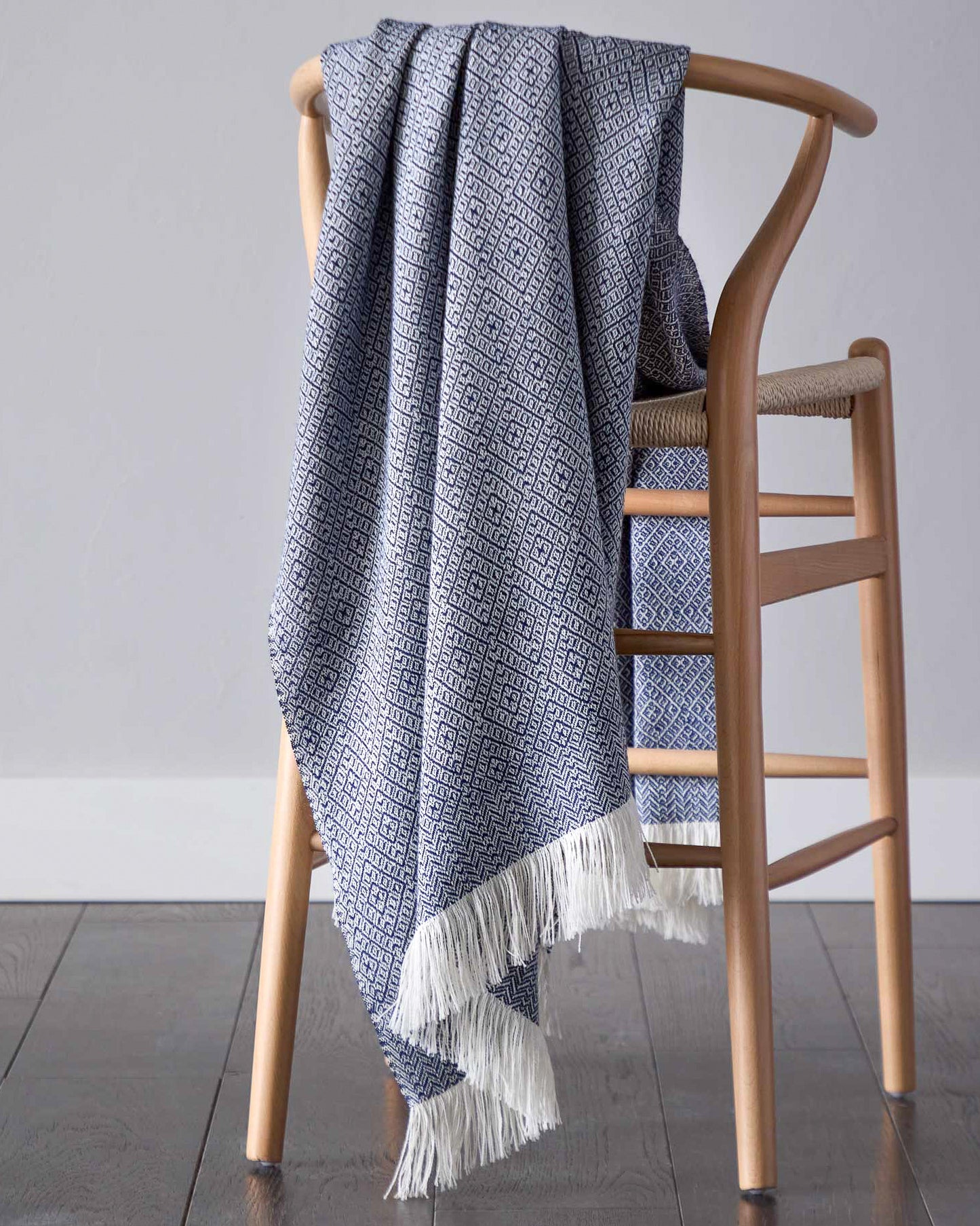 
                  
                    Styled navy blue baby alpaca throw blanket with white fringe modern design handcrafted by artisans in Peru.
                  
                