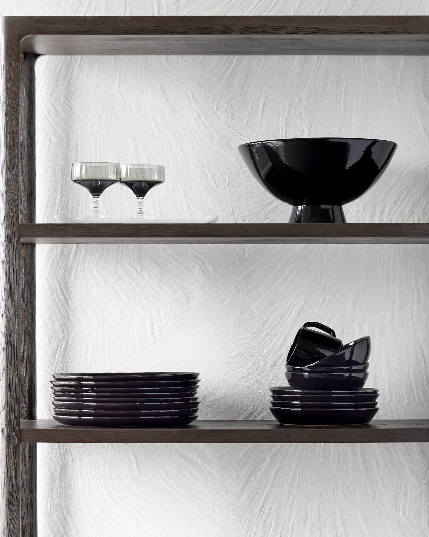 
                  
                    Fairkind Riad Dinnerware and Rami Pedestal Bowl in black stacked on floating kitchen shelves.
                  
                