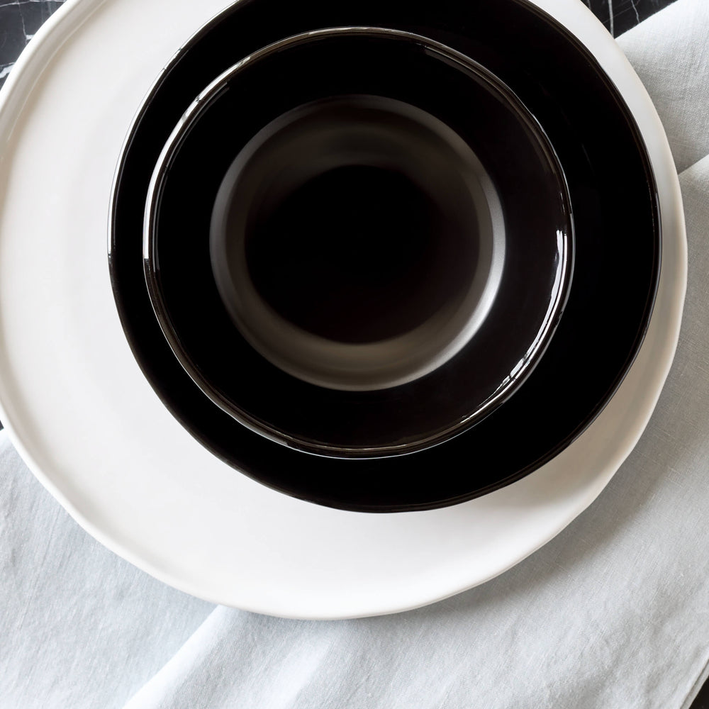 
                  
                    Riad Soup Bowl styled with white and black plates on a marble dining table.
                  
                