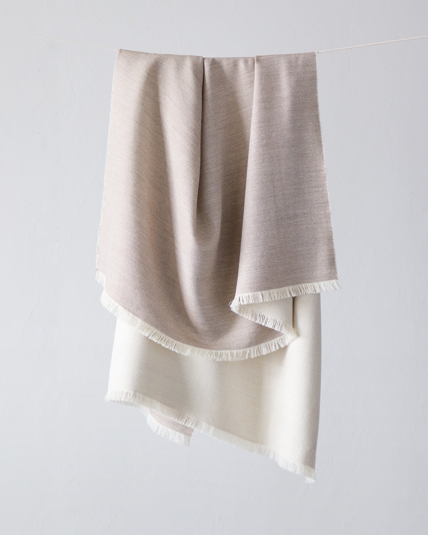 
                  
                    Fairkind Soñando sand alpaca throw blanket beige tan base with white back and fringe by Fairkind.
                  
                