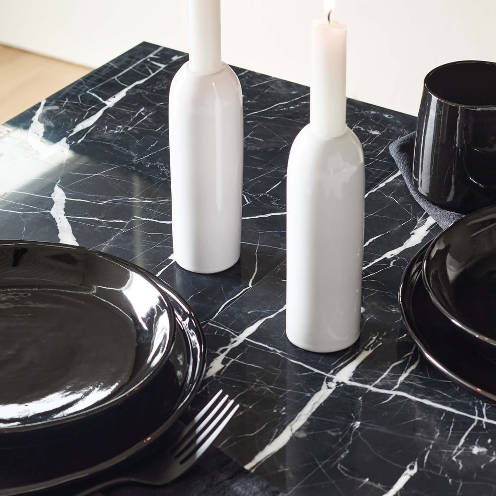 
                  
                    Yasmine Taper Holders in white styled with black dinnerware on a modern marble table. 
                  
                
